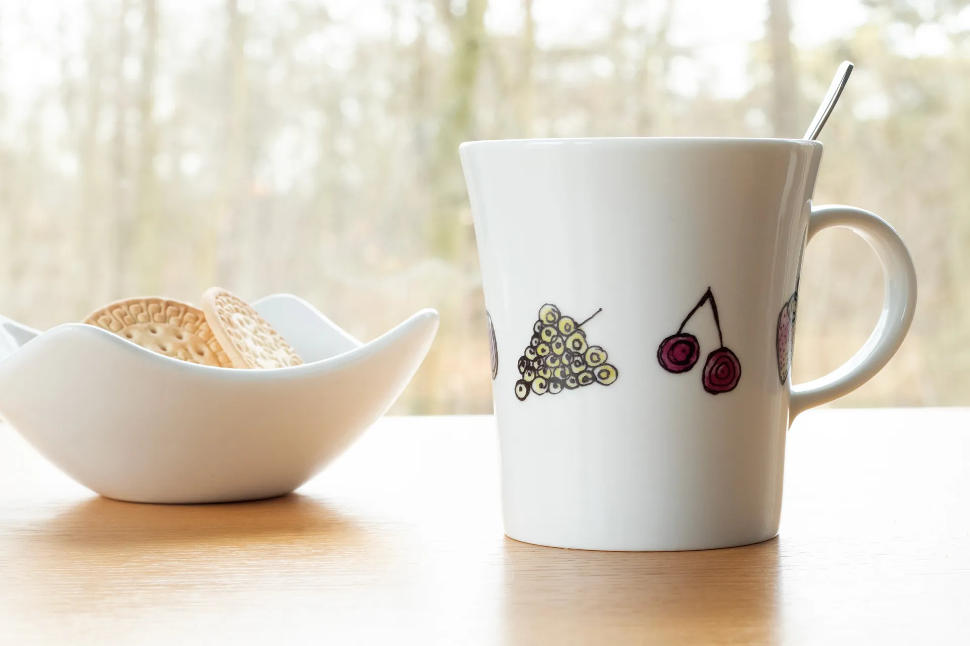 Weiße Porzellantasse mit farbintensivem, handgezeichnetem Früchte-Motiv (z. B. Beeren, Zitrusfrüchte) rundum als Dekor, 0,28 l