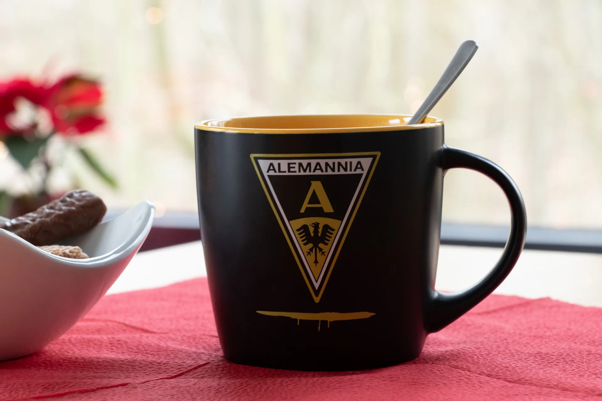 Schwarze matte Porzellantasse mit gelber Innenseite, mit einem Motiv zum Aufstiegslied „Aus meinem Traum bin ich heute aufgewacht…“ und dem Schriftzug „Alemannia“, 0,27 l